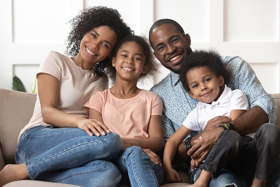 Personal Insurance - Portrait of Happy Family with Children Relaxing on the Couch in Their Living Room